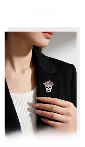 Detail view of a skull brooch with floral accents on a black blazer.