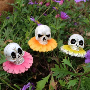 Detailansicht von drei Totenkopf-Blumensteckern aus Harz in einem natürlichen Beet