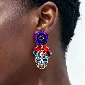 Detail eines farbenfrohen Halloween-Totenkopf-Ohrrings mit Emaille-Blumen und Strasssteinen am Ohr