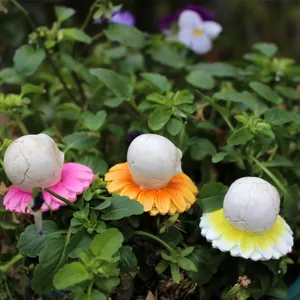Detailansicht von drei dekorativen Harz-Totenkopf-Blumensteckern in natürlichem Laub.