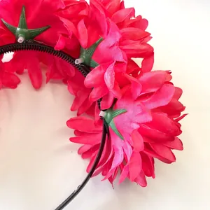 Detail of vibrant pink simulated marigold flowers on a black toothed headband.