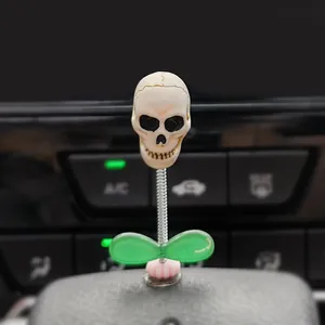 Close-up view of a spooky skull bobblehead ornament mounted on a car dashboard console.