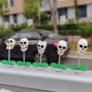 A detailed view of five Halloween skull car bobblehead ornaments with springs and bats