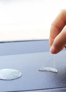 Close-up detail of a transparent silicone adhesive pad being peeled from a car dashboard