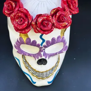 Detailed close-up of a painted resin skull with red glittery roses for Halloween decor.