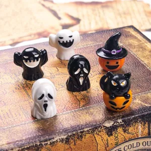 Close-up of miniature Halloween resin charms with ghost and pumpkin designs