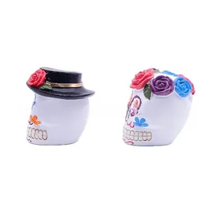 Detailed side view of two colorful Day of the Dead resin sugar skull festive figurines