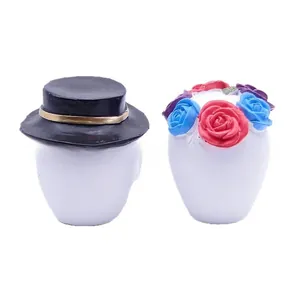 Detail view of Mexican Day of the Dead resin sugar skull figurines with hat and flowers