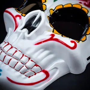 Close-up macro view of a white Mexican Day of the Dead skull mask with colorful floral patterns