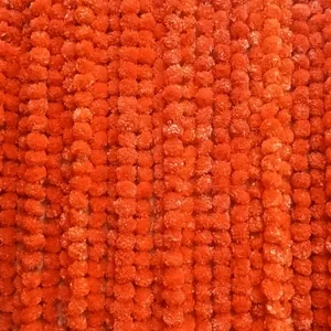 Gros plan détaillé montrant la texture dense des guirlandes de soucis artificiels orange