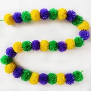 Top-down view of colorful marigold garland with yellow, purple, and green pom-poms