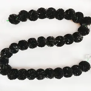 Detailed view of black plastic marigold garland for Day of the Dead and wedding decor.