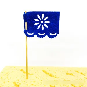 Close-up view of a blue felt papel picado cake topper for Day of the Dead party decor.