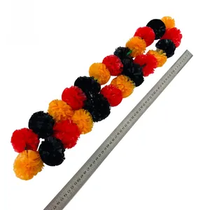 Detailed view of multi-colored marigold garland showing size with a metal ruler scale