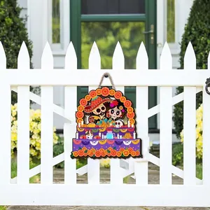 Decorative Day of the Dead wooden hanging sign displayed on a white picket fence outdoors