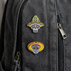 Detail of Mexican sugar skull enamel pins with sombreros on a canvas backpack