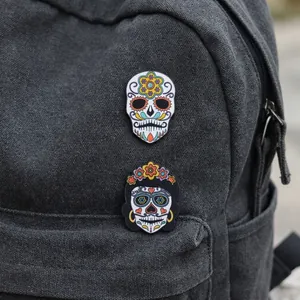 Detail of colorful Mexican sugar skull enamel pins attached to a grey canvas backpack