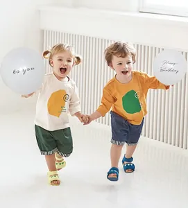 Toddlers holding Happy Birthday balloons in cute casual summer outfits for festive parties.