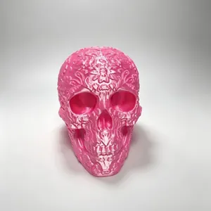 Pink 3D printed floral skull ornament with Day of the Dead carvings on white background.