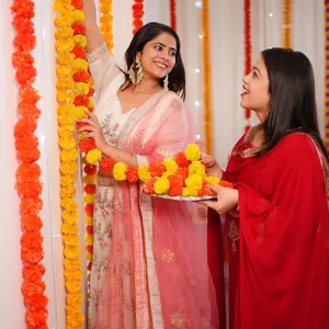 Indian women decorating a festive background with vibrant orange and yellow marigold garlands