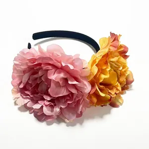 Detailed view of oversized pink and orange artificial peony flowers on a black headband