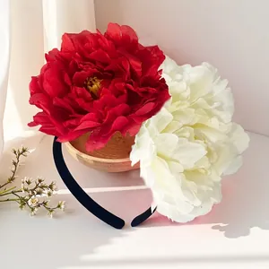Close-up detail of oversized 12cm red and white artificial camellia flower bridal headband