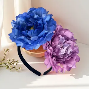 Detailed view of an oversized artificial camellia headband with blue and purple flowers