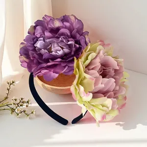 Macro view of large purple and pink artificial peony flowers on a black bridal headband