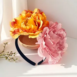 Close-up of vibrant 12cm artificial camellia flowers on a black headband accessory