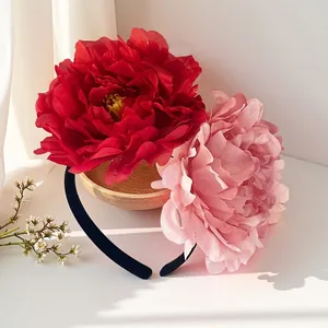 Detail of oversized red and pink artificial camellia flowers on a black headband