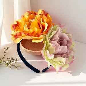Close-up of a decorative headband with large orange and pink artificial camellia flowers.