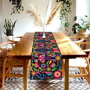 Detailed close-up view of colorful Mexican floral linen table runner on a rustic dining table