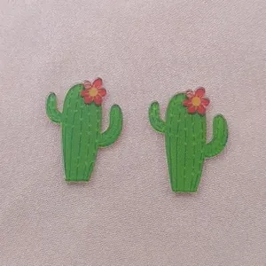 Detail view of green acrylic cactus charms with red flower accents for DIY jewelry