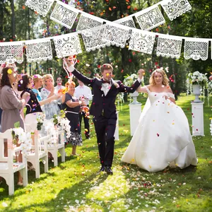 White Mexican Papel Picado felt banner used as wedding decoration in an outdoor garden