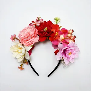 Nahaufnahme eines bunten Blumen-Haarreifens mit roten, rosa und cremefarbenen Blüten.