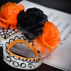 Zoom sur le masque Jour des Morts avec roses orange et noires et paillettes.