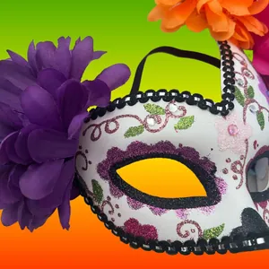 Vue détaillée d'un masque mexicain Jour des Morts avec paillettes et fleurs violettes.