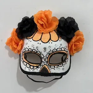 Close-up of a Day of the Dead mask decorated with orange and black fabric roses