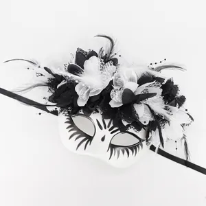 Close-up of Mexican Day of the Dead mask with black and white flowers and feathers