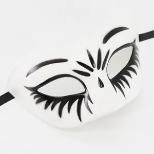 Close-up detail of a white masquerade mask featuring elegant black painted eyelash patterns