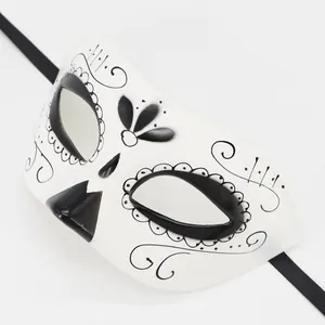 Close-up detail of white Day of the Dead mask with intricate black floral patterns.