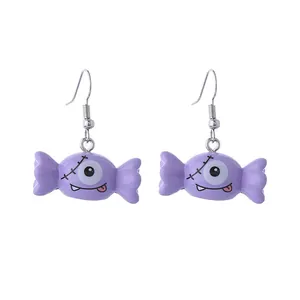 Vue détaillée des boucles d'oreilles bonbons d'Halloween violettes avec visage de monstre.