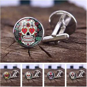 Detailweergave van zilveren manchetknopen met kleurrijke Mexicaanse suikerschedels.