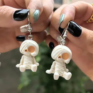 Détail en gros plan de boucles d'oreilles momie blanche tenues à la main pour Halloween