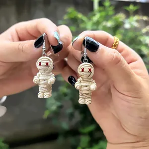 Détail de boucles d'oreilles momie d'Halloween mignonnes avec yeux en X rouges en main