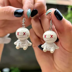 Détail de boucles d'oreilles momie d'Halloween avec bandages blancs et yeux rouges en X