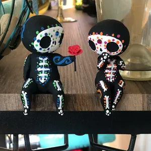 Detailansicht zweier bunter Zuckerschädel-Skelettfiguren, die auf einem Regal sitzen