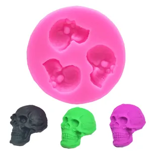 Detailed view of a pink silicone skull mold showing three multicolored resin skulls.