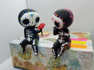 Zwei handgefertigte Zuckerschädel-Figuren auf einer Box, Tag der Toten Dekoration.