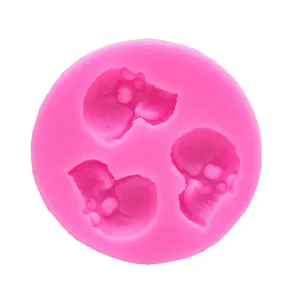 Detailed macro view of a pink silicone mold featuring three skull-shaped cavities.